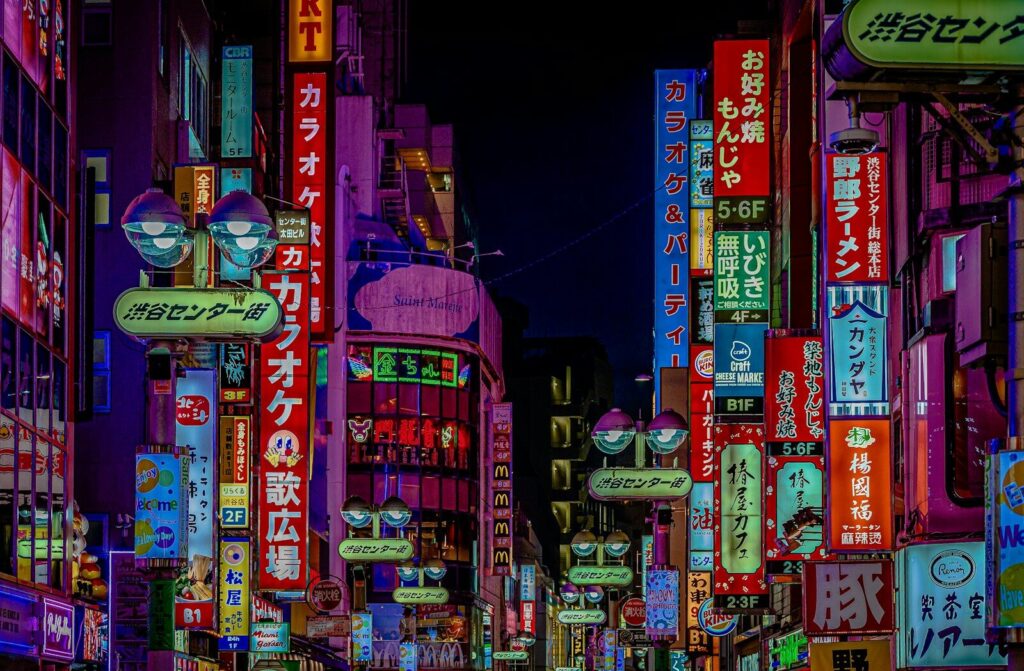 Bright neon signs in Japanese characters lining a narrow street in Shibuya, Tokyo