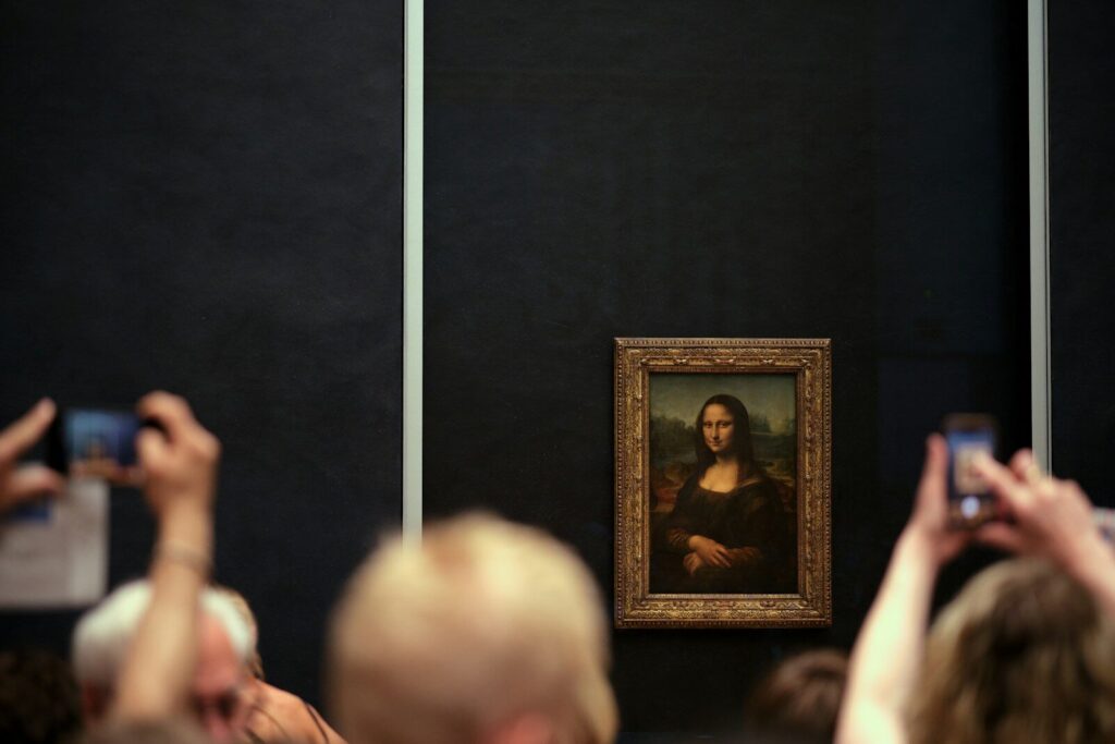 The Mona Lisa painting in a gold frame on a dark wall with visitors
